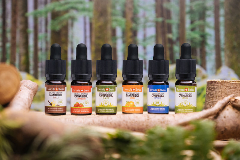 Sechs Vollspektrum-CBD-Öle von Formula Swiss in verschiedenen Trägerölen und Geschmacksrichtungen vor einem Wald