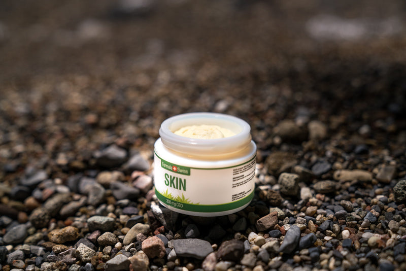 Geöffneter Tiegel CBD Skin Balsam von Formula Swiss, 300 mg CBD, an einem Kieselstrand