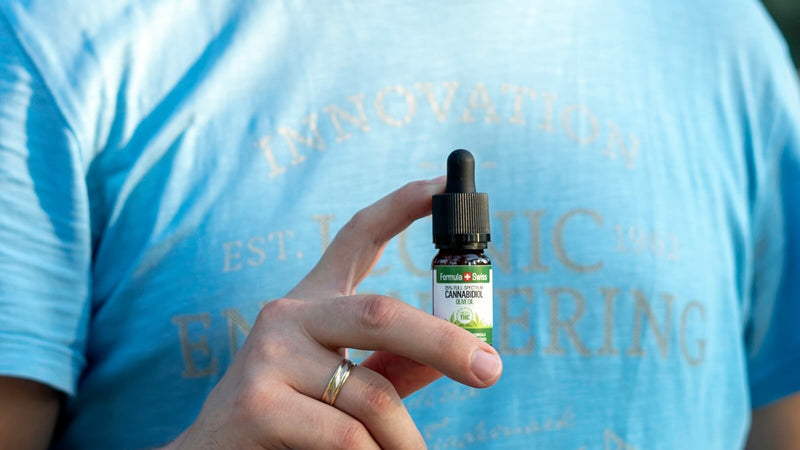 Eine Hand hält eine 10-ml-Flasche CBD-Öl in Olivenöl von Formula Swiss