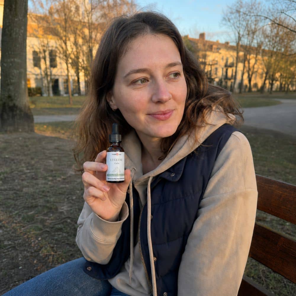 Frau hält eine Flasche CBD-Öl Lucerne im Freien in einem Park